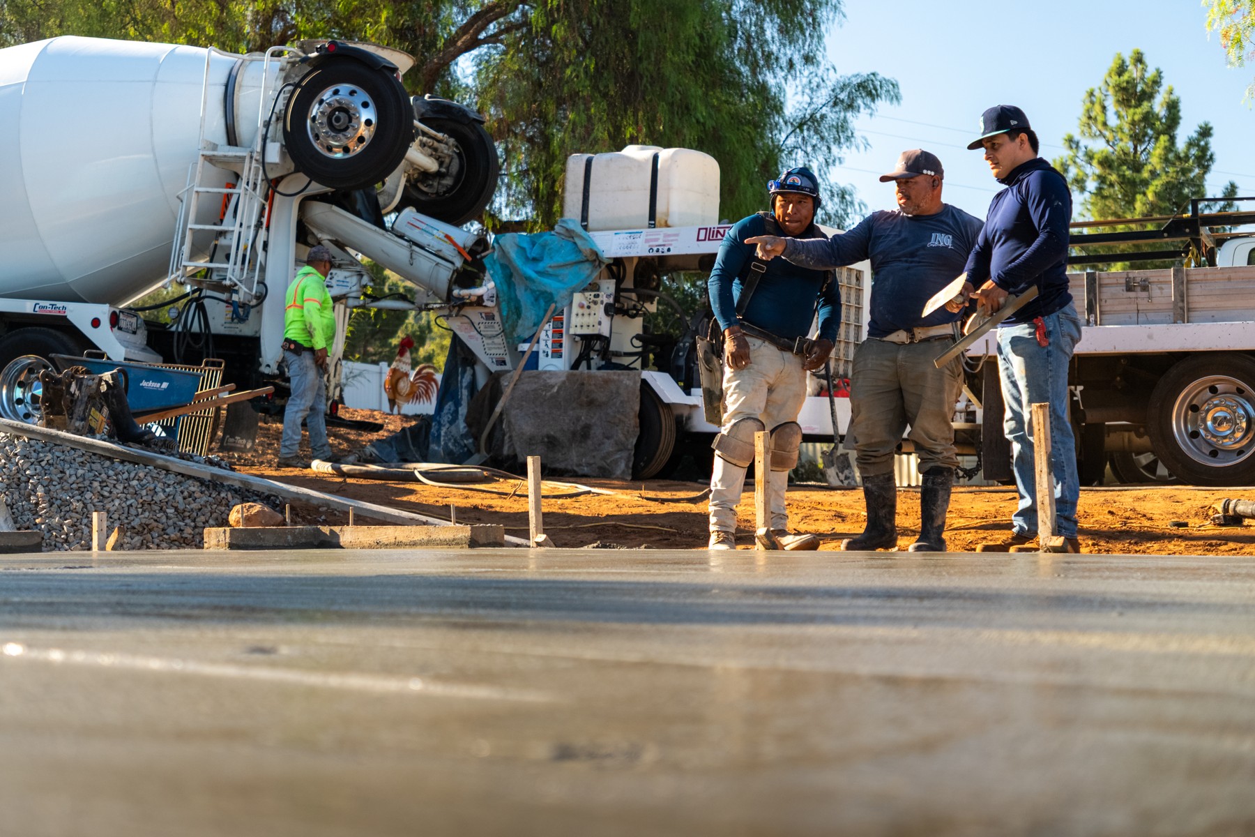 Concrete crew coordinating a pour beside a mixer truck and freshly poured slab